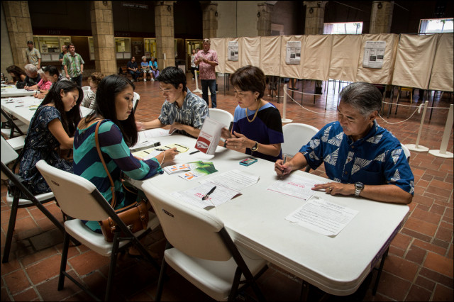 Sen. David Ige, with wife Dawn and three children left to right, Amy, Lauren and Matthew fill out forms to vote early at Honolulu Hale on August 5, 2014