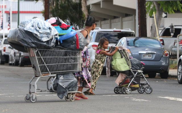 Families move their personal belongings on carts along Ahui Street as city workers sweep on Ilalo Street last October. Hawaii's homeless crisis is now deemed worst in the nation. 