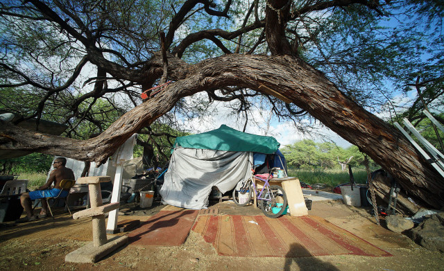 Jay sits in his camp area complete with falling kiawe tree. 
